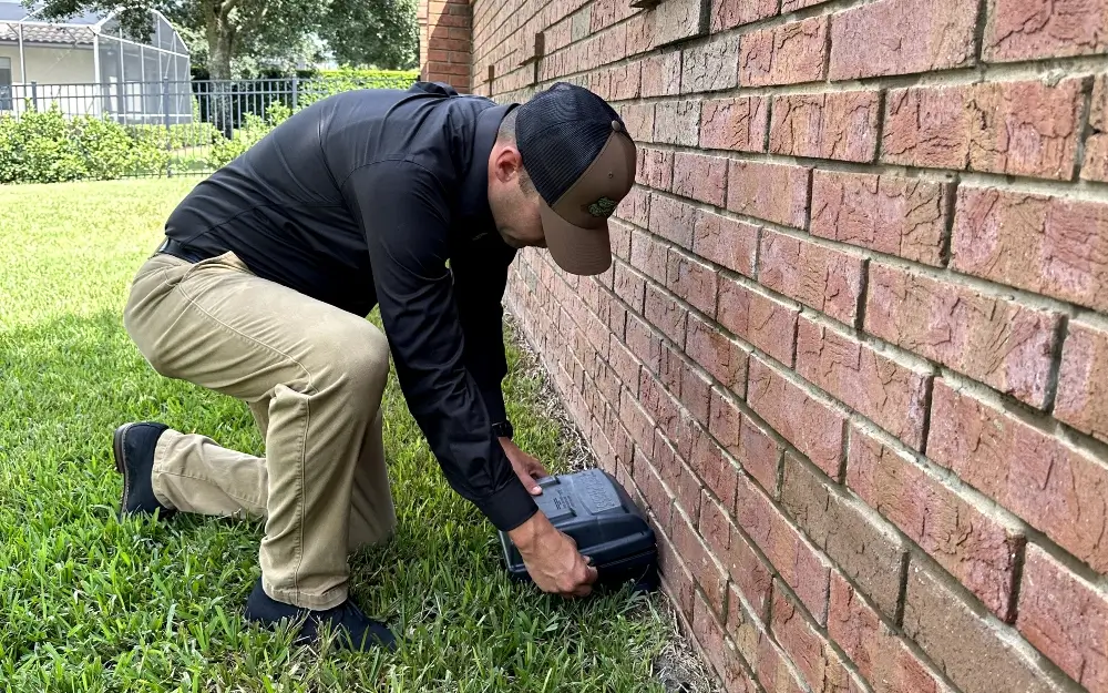 A Sorko Services worker placing a rodent trap on the outside of a building.