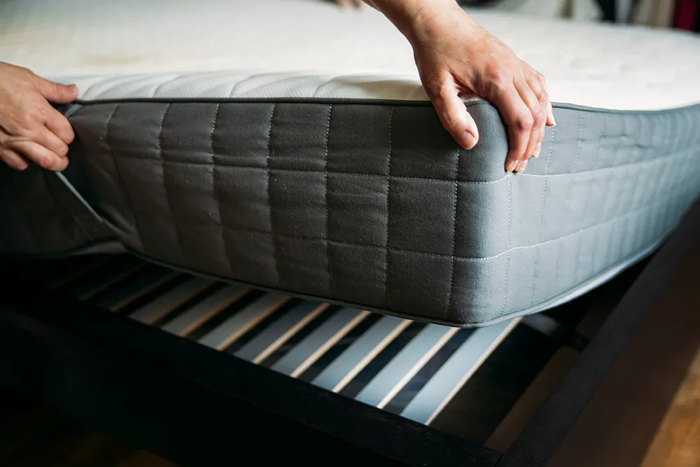 Person applying a mattress cover to a bed